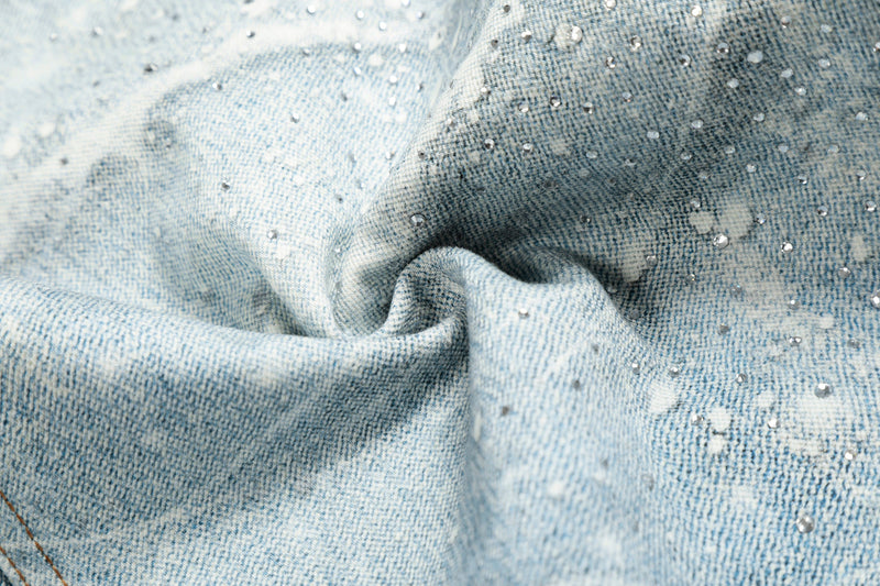 Close-up of crumpled light blue denim with white spiderweb wash and bead-like speckling