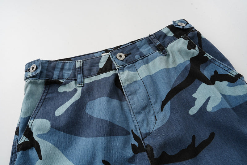 Top front waist detail of blue camouflage shorts with belt loops and button closure