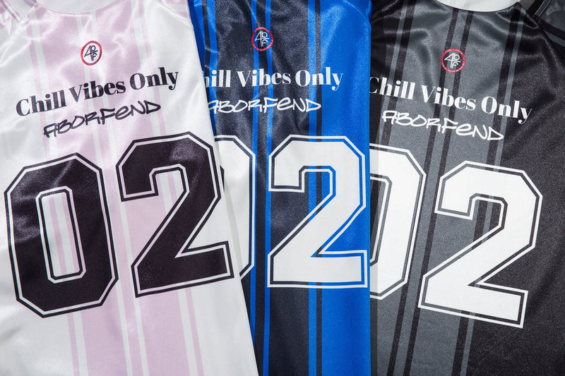 Three versions of the long sleeve jersey top in white, blue, and black with front graphics