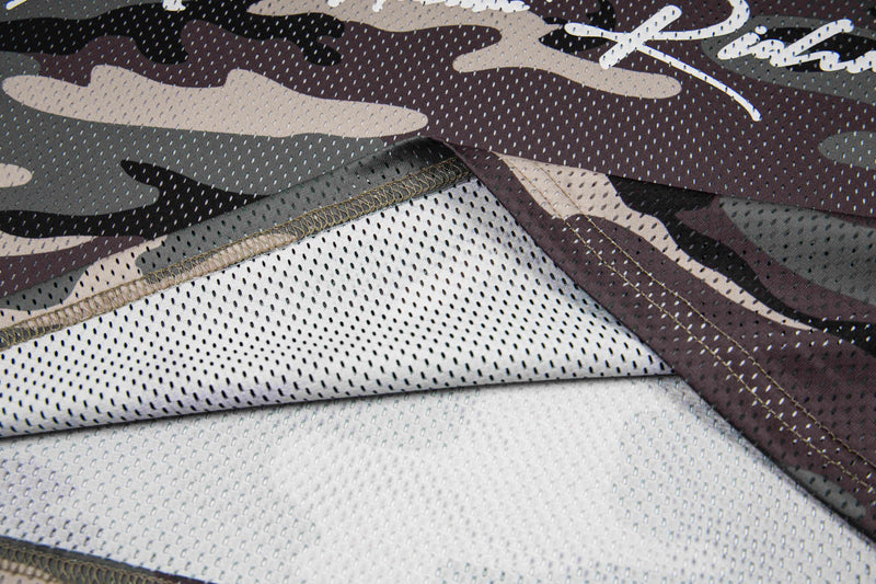 Close-up of camo mesh football jersey fabric with oversized streetwear pattern and visible stitched seams