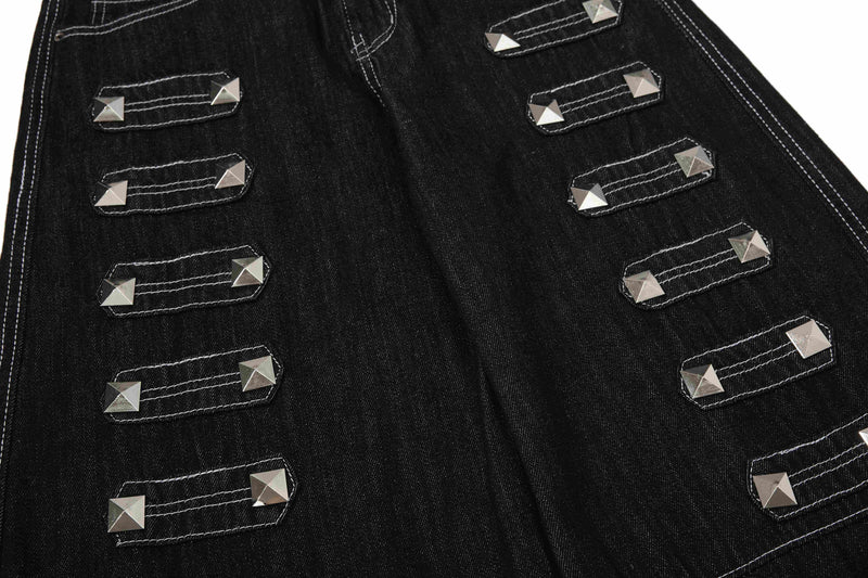 Close-up of black denim pant legs with rows of silver studded strap accents