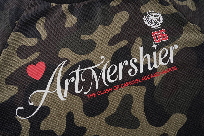 Front chest of camo jersey showing ArtMershier script, red heart, and 06 crest