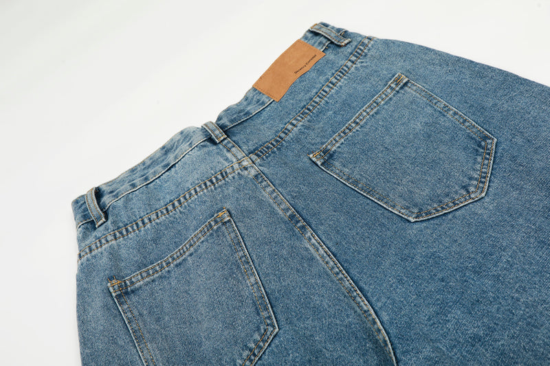 Back view close-up of blue denim jeans with tan label and patch pocket