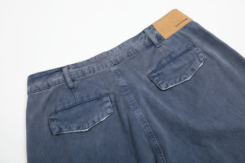 Back waistband of washed blue cargo pants with tan patch labeled Decency Concept