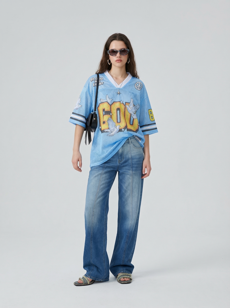 Light blue mesh jersey T-shirt with bold graphic print, oversized fit, and loose wide-leg jeans on a model