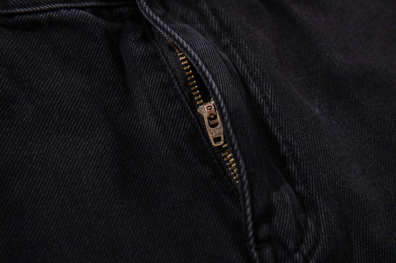 Close-up of brass zipper on black denim carpenter jeans