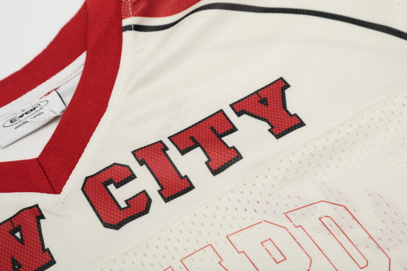Close-up of a white mesh football jersey with red trim and bold CITY lettering in varsity style print