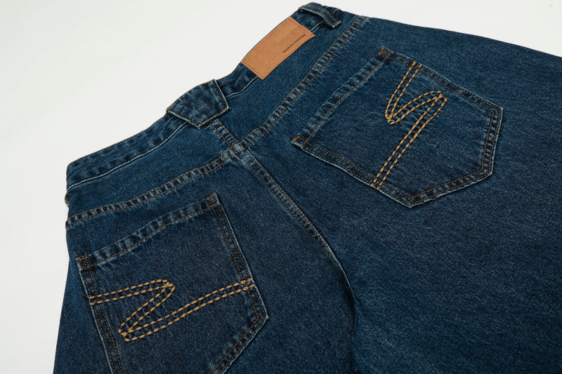 Close-up of the back waistband and stitched pocket details on dark indigo jeans