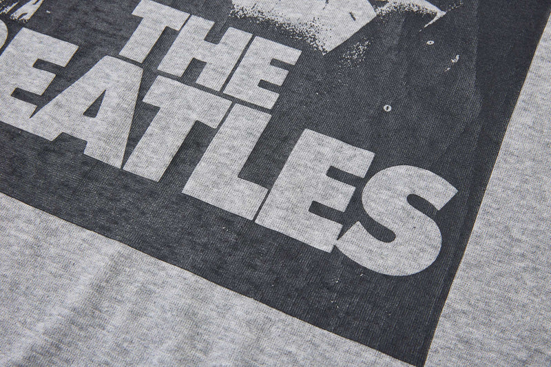 Close-up of a vintage Beatles graphic on a gray contrast-sleeve T-shirt with bold black-and-white distressed print