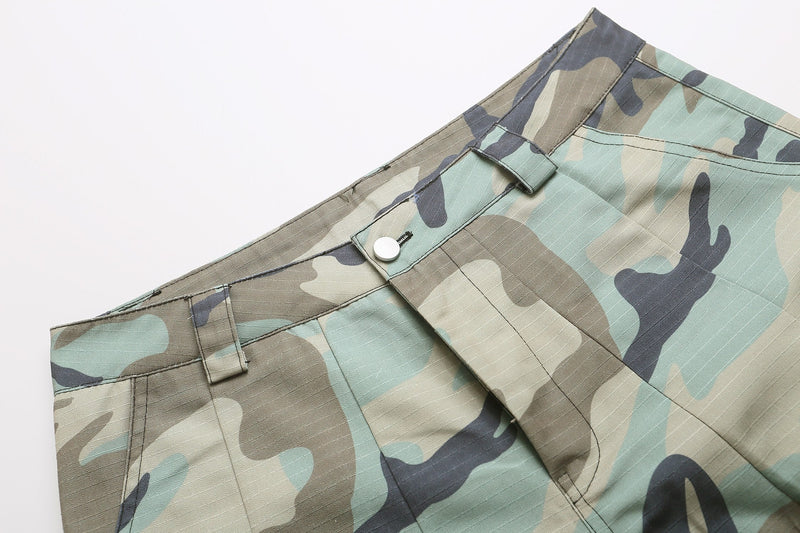 Close-up of camo shorts waistband with belt loops, button closure, and front pocket edge
