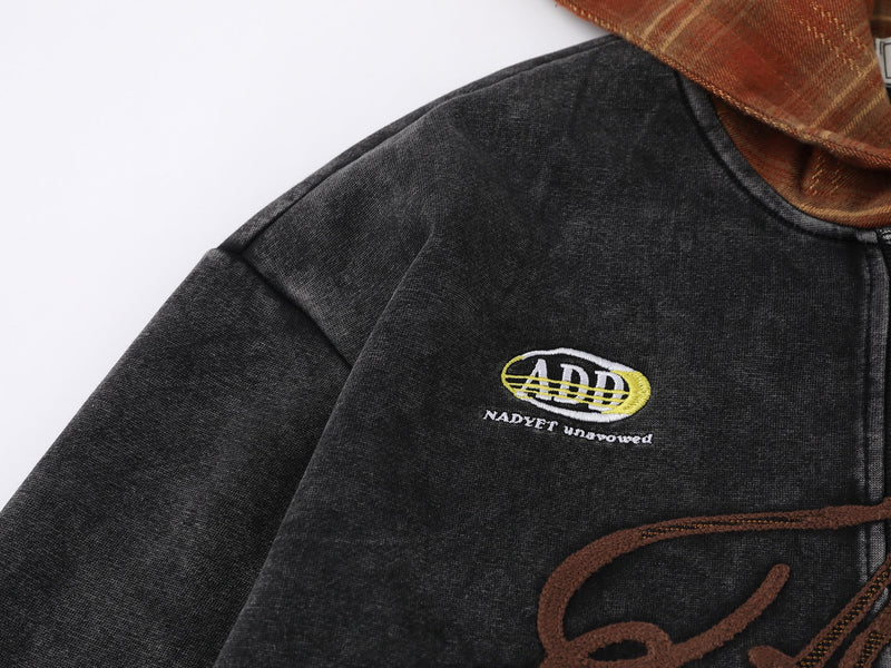 Close-up of black jacket shoulder with ADD patch and plaid hood edge
