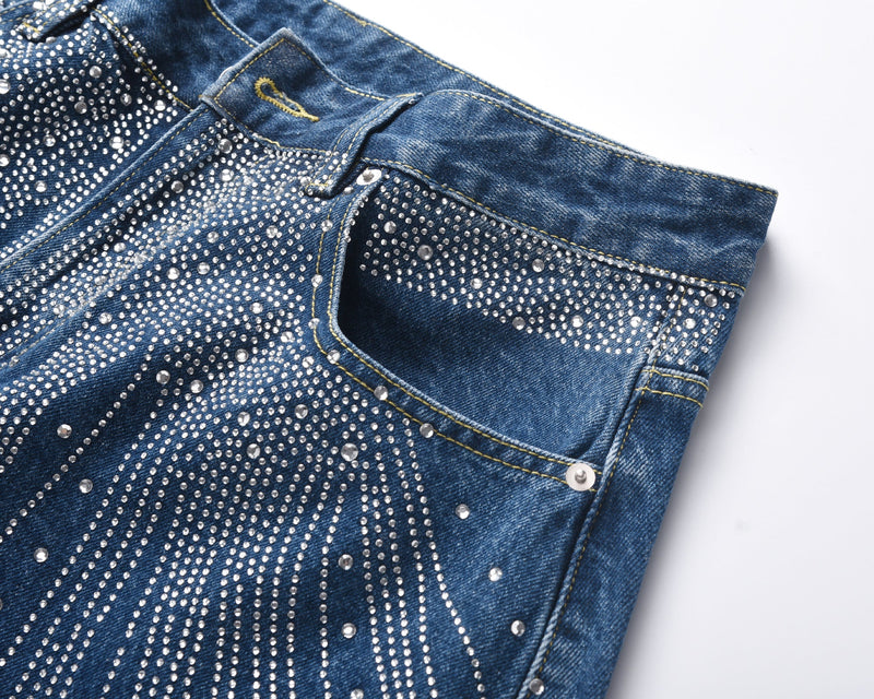 Angled close-up of blue denim waistband and front pocket with rhinestone embellishment