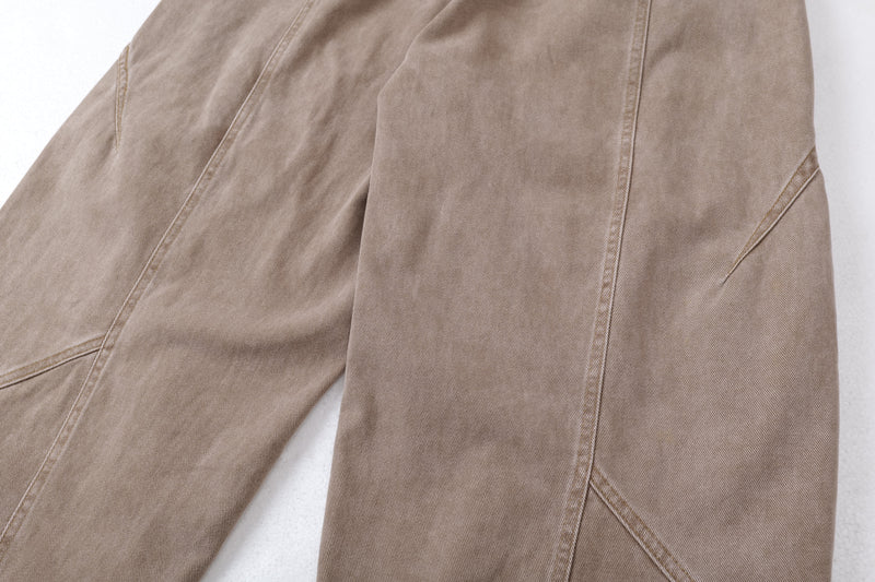 Close-up of tan jeans leg with curved seam panel and wide cut