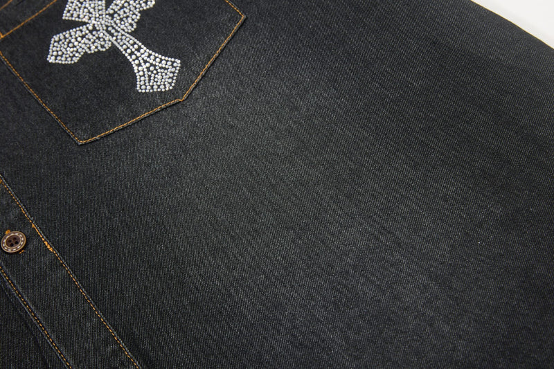 Close-up of black denim shirt with rhinestone cross detail, orange contrast stitching, and button-up front