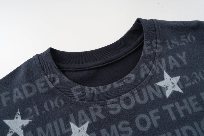Dark navy graphic T-shirt with faded allover text and star print, featuring a ribbed crew neck and distressed look