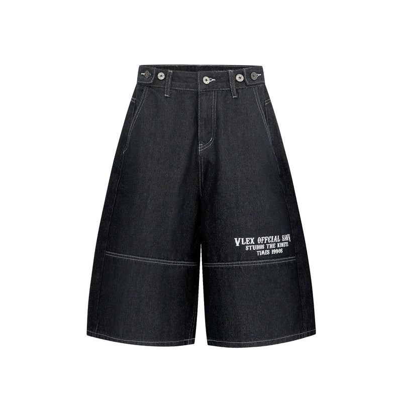 Black oversized denim shorts front view with wide legs and white printed hem text