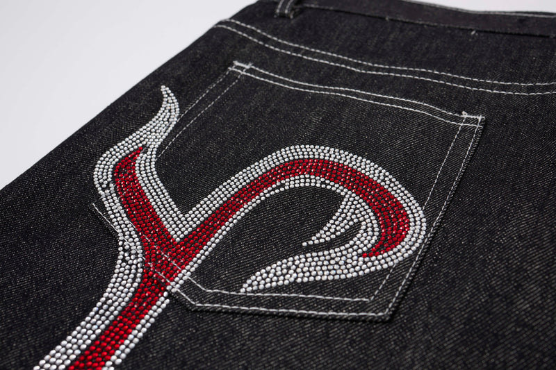 Close-up of back pocket on black denim pants with red and silver rhinestone flame detail