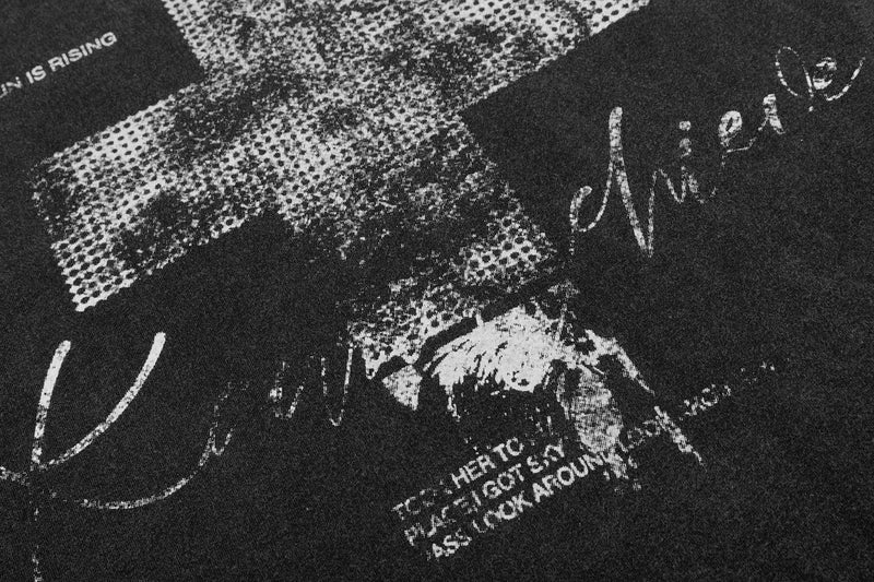 Close-up of a black washed graphic tee with distressed white cross and vintage-style text print