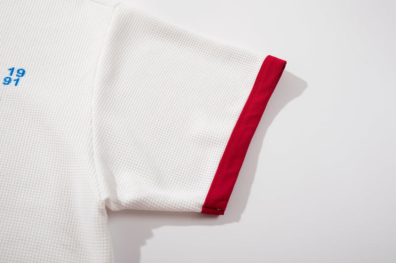 White waffle-knit ringer T-shirt sleeve with red trim and small blue 1991 graphic detail