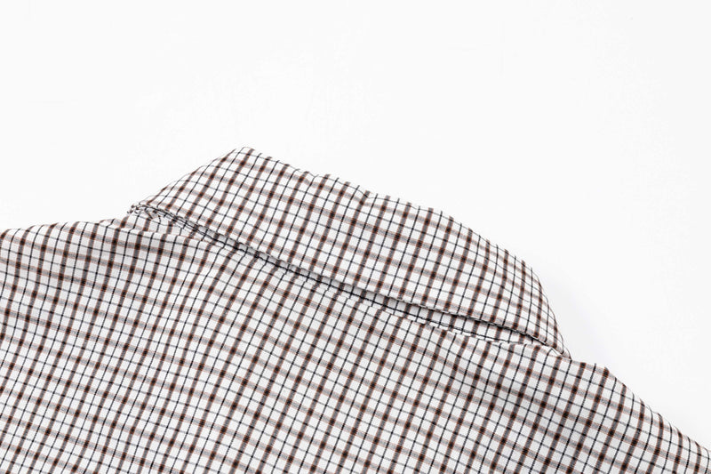 Folded oversized polo shirt in white plaid with brown and black check pattern on a clean white background