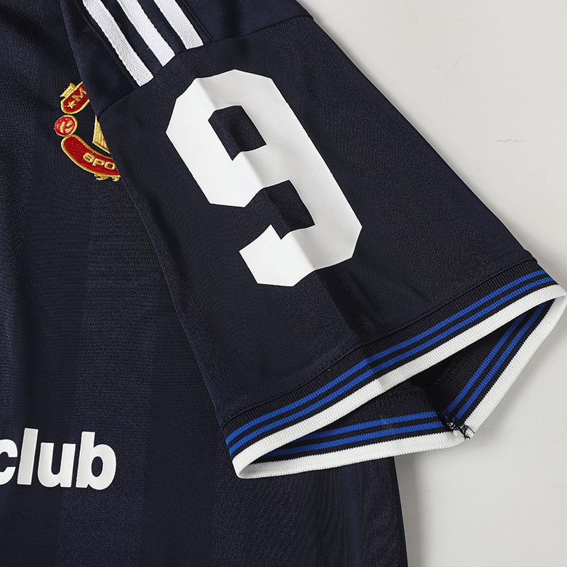 Navy soccer jersey with white number 9, club crest, and striped sleeve cuff detailing