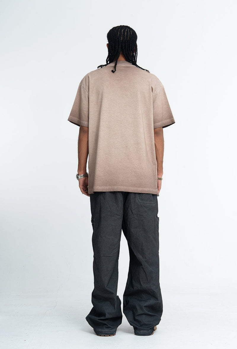 Back view of a beige vintage wash oversized graphic tee with black pants on a model against a white background