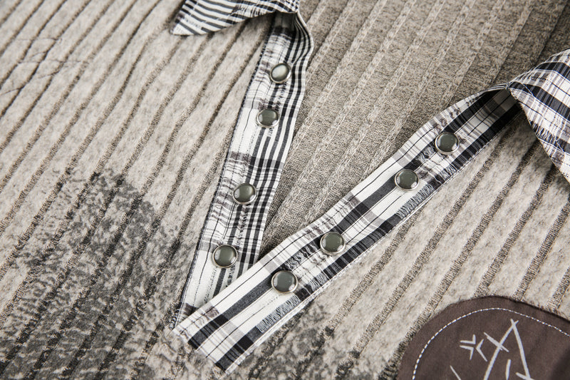 Close-up of beige ribbed knit V-neck with plaid trim and metal snap buttons