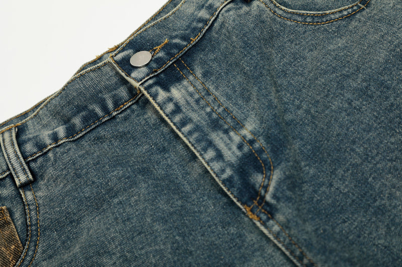 Close-up of blue denim waistband seam with metal button and top stitching