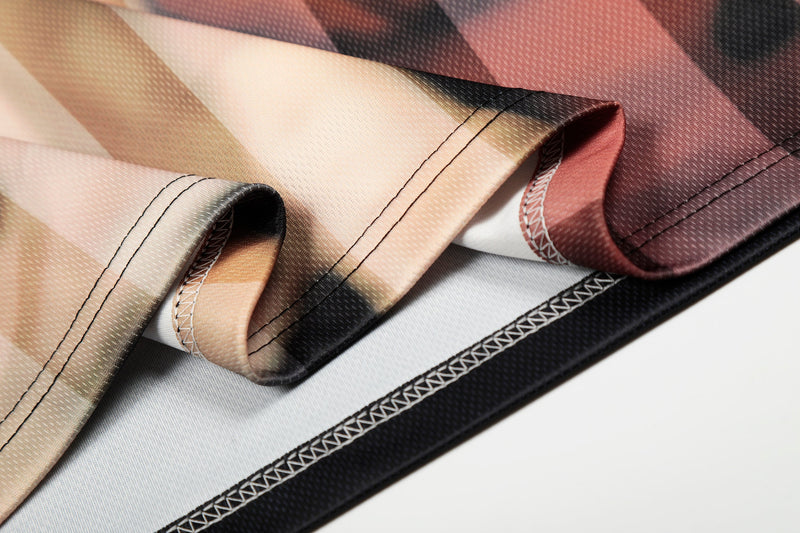 Close-up of folded abstract portrait mesh jersey with oversized streetwear print and stitched hem detailing