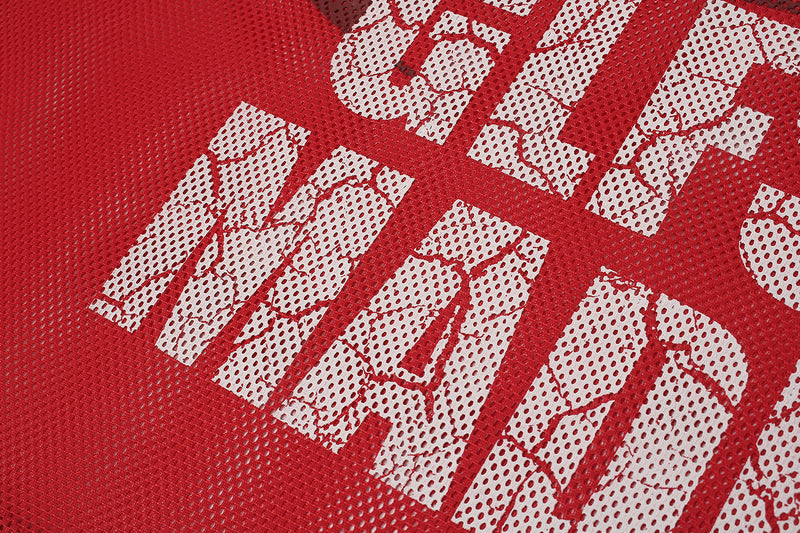 Close-up of a red oversized mesh football jersey with distressed white graphic lettering and perforated fabric texture