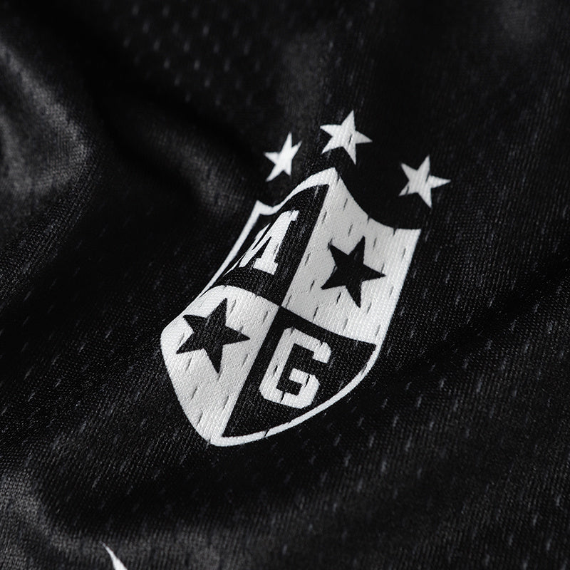 Close-up of black mesh jersey fabric with a white gothic varsity crest and star details