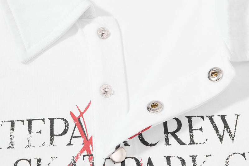 White distressed graphic polo shirt with snap buttons and bold skatepark crew lettering print