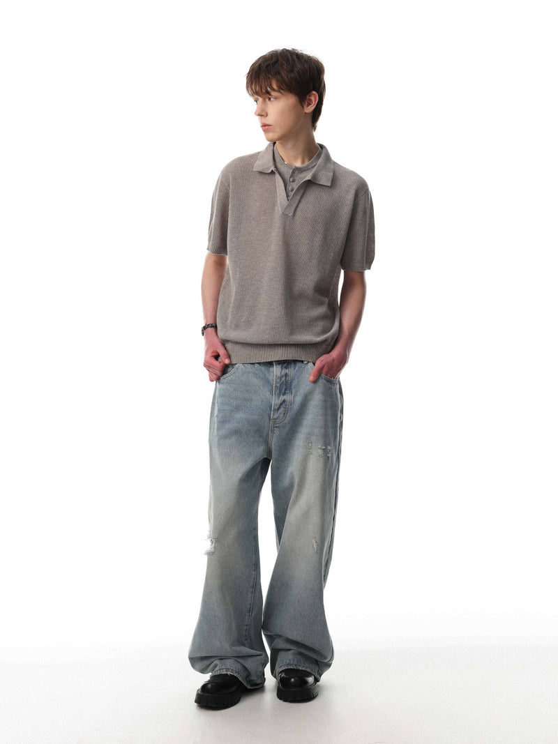 Men’s gray open knit polo shirt styled with wide-leg jeans on a white background