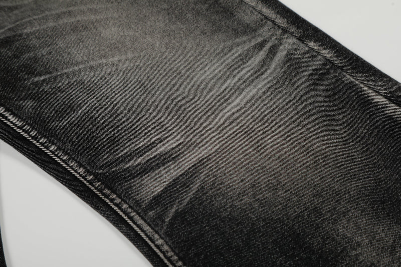 Close-up of faded black denim fabric with diagonal whiskering on the leg