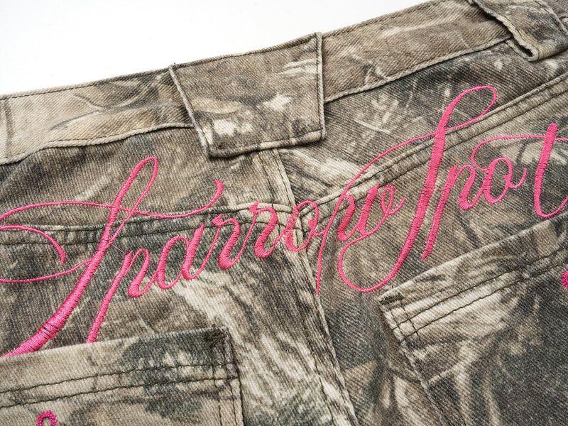 Close-up of back waistband and pink script embroidery on camouflage pants