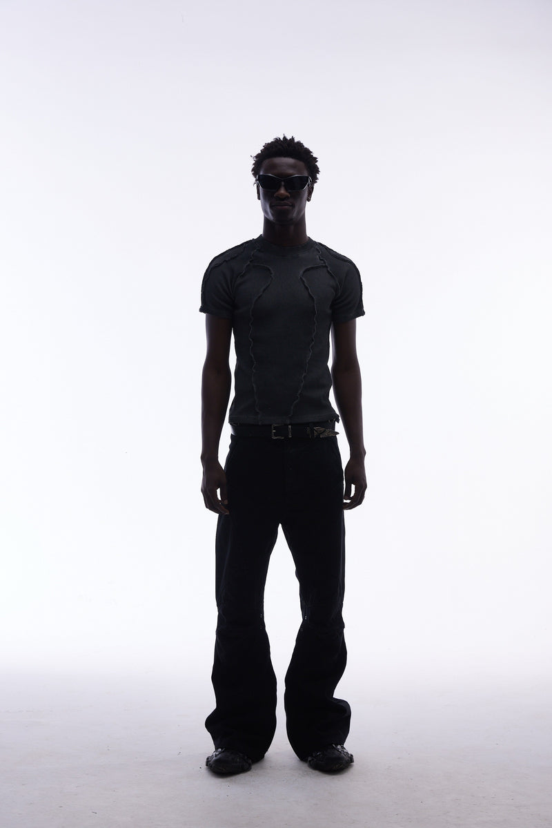 Black raw seam compression tee styled with dark cargo pants and sunglasses on a minimalist white background