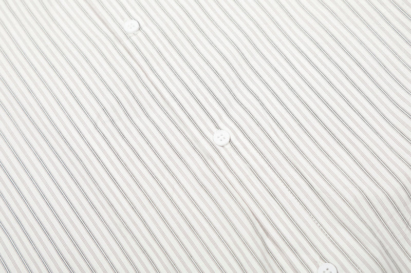 Close-up of cream shirt front with narrow vertical pinstripes and white buttons