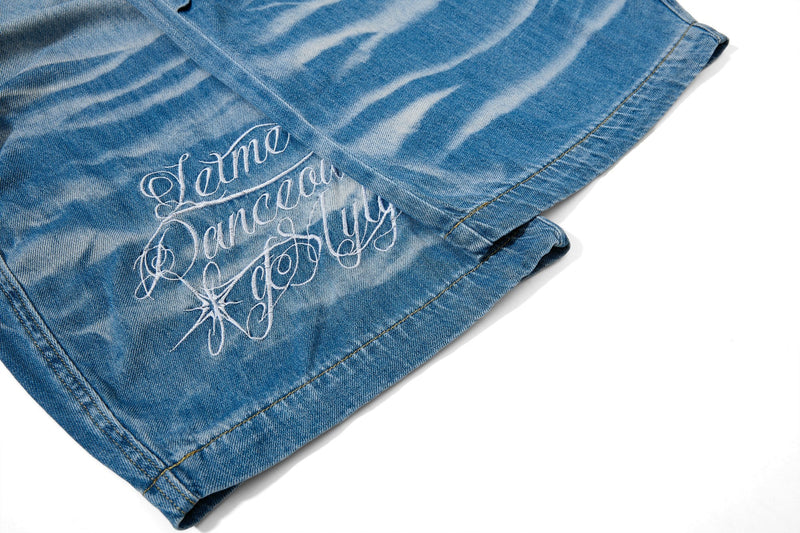 Close-up of embroidered script graphic near the hem of light wash baggy jeans