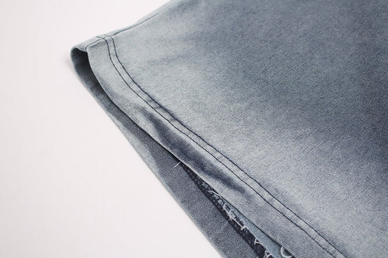 Close-up of a washed denim-style vintage graphic T-shirt hem with faded blue-gray fabric and visible stitching