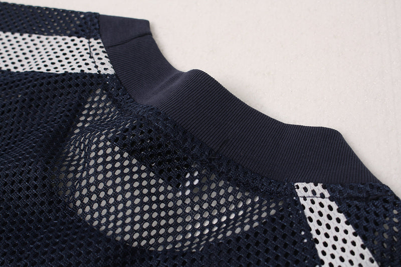 Close-up of a navy oversized varsity mesh jersey with ribbed collar and black-and-white perforated panels