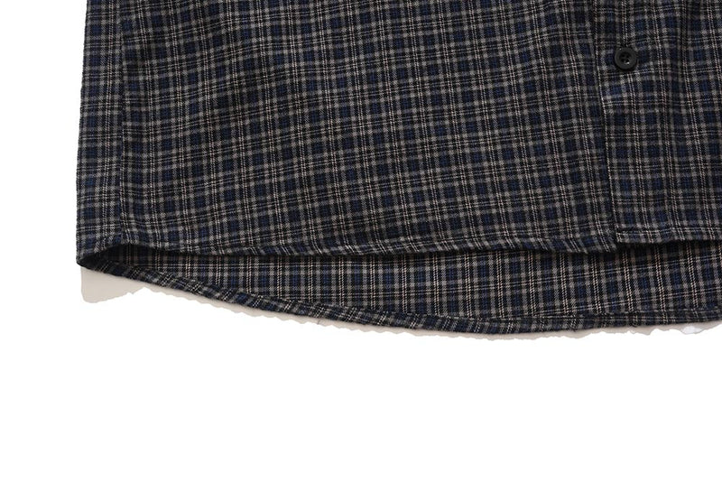 Close-up of curved hem and button front on dark plaid sleeveless shirt