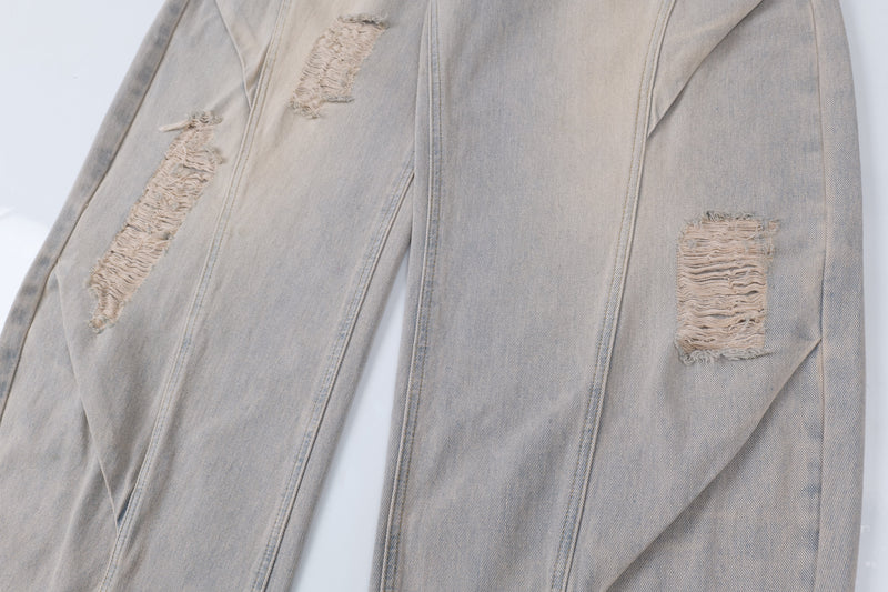 Close-up of wide-leg jeans showing frayed distressing patches on the front legs