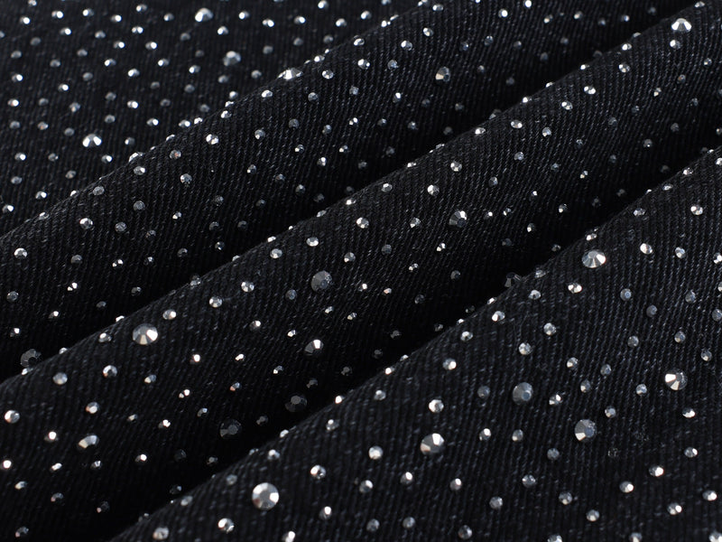 Black denim fabric close-up covered in small rhinestones