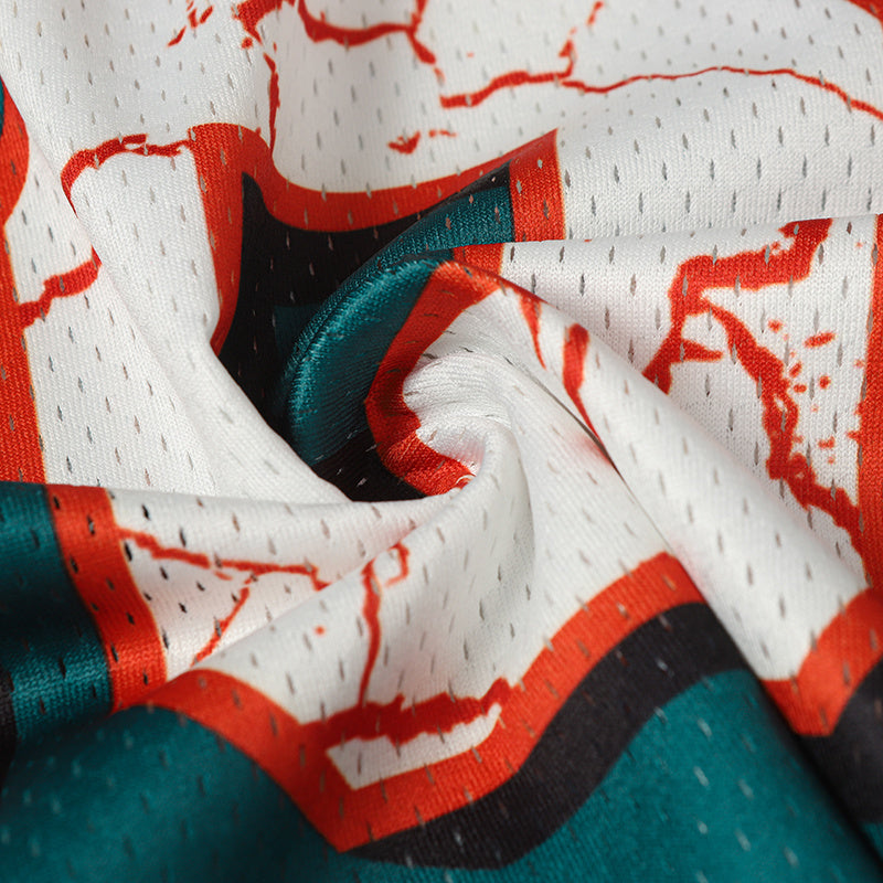 Close-up of a white football jersey fabric with red cracked number print, teal accents, and black trim details