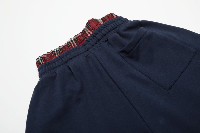 Back pocket close-up on navy shorts with red plaid waistband above