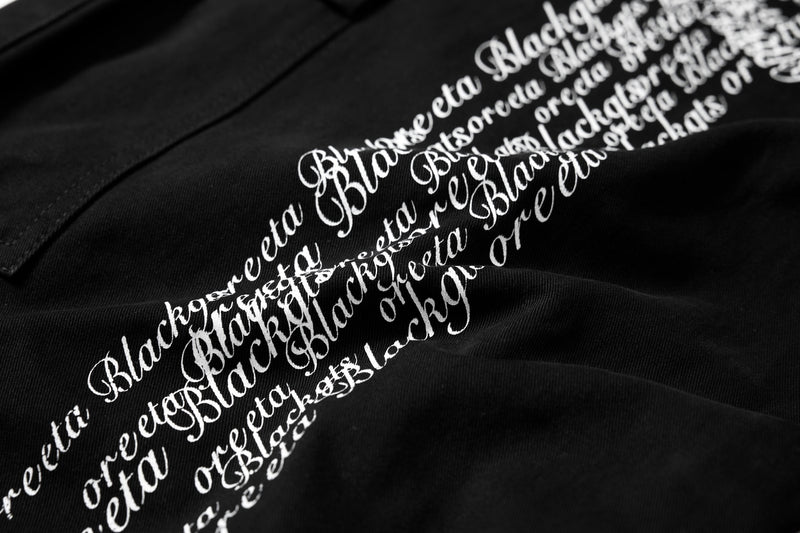 Close-up of white cross script print on black cargo pants