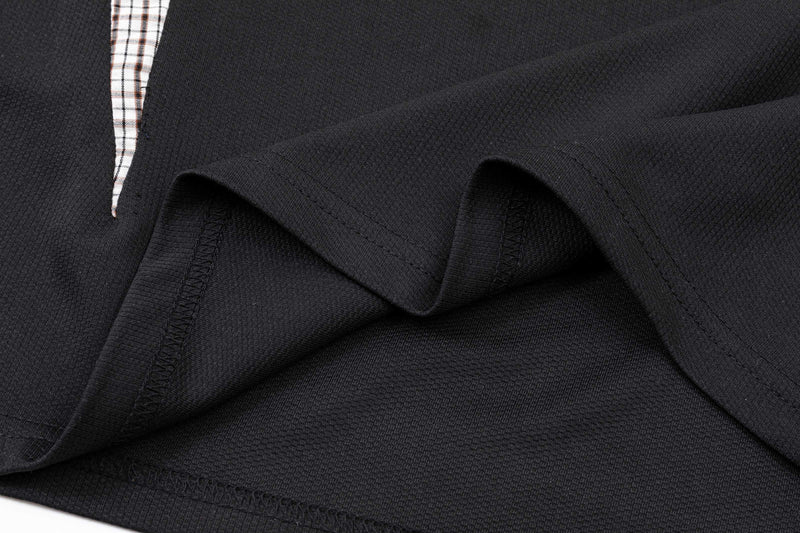 Close-up of a black oversized polo shirt with plaid panel detail and textured knit fabric