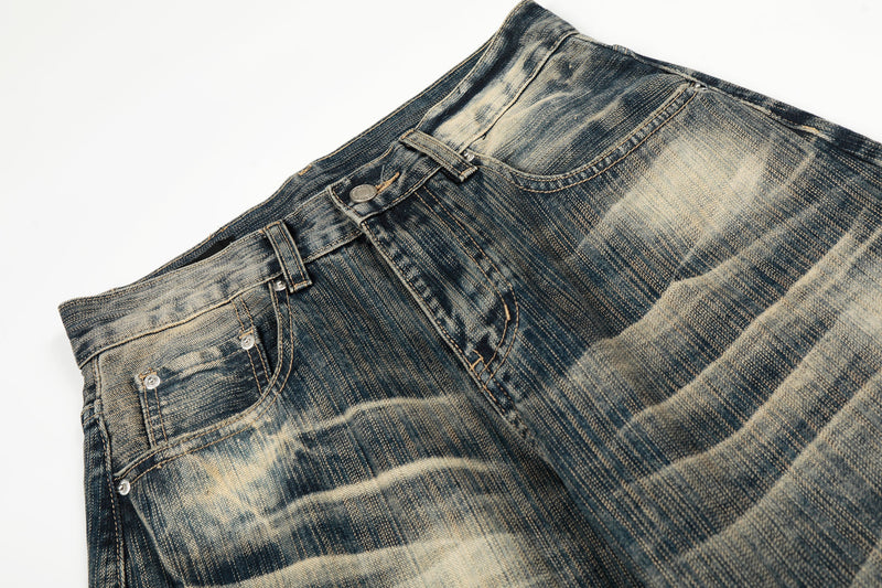 Close-up of the front waist on washed denim pants with button closure and belt loops