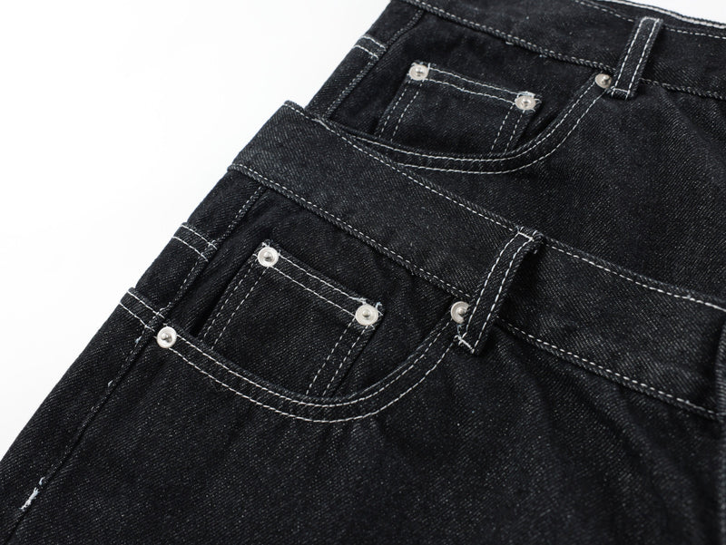 Close-up of front pocket and waist seam details on black denim pants