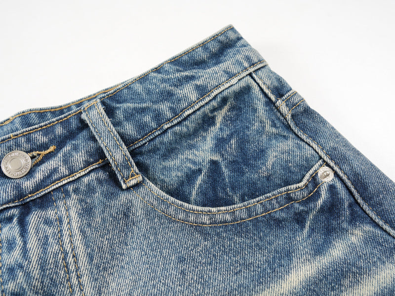 Close-up of the back waistband and pocket edge on faded blue denim shorts